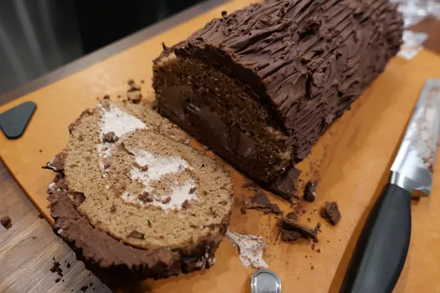 A yule log cake with one slice cut.